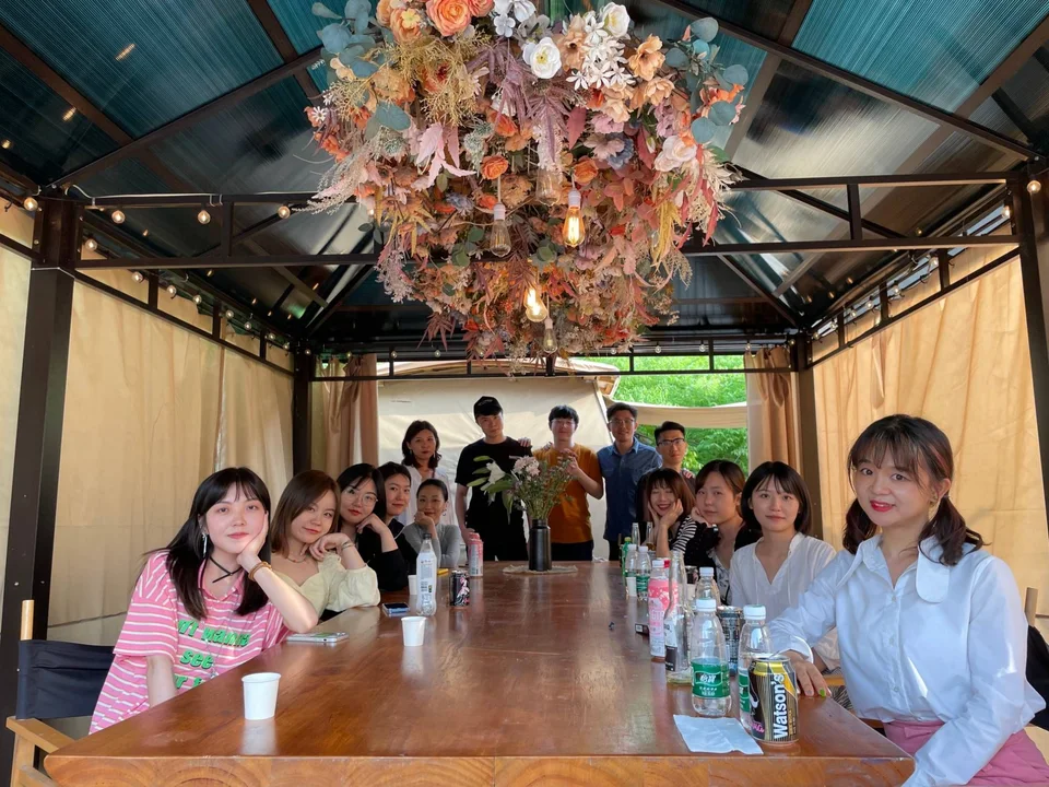 Colleagues around a long table under a flower chandelier